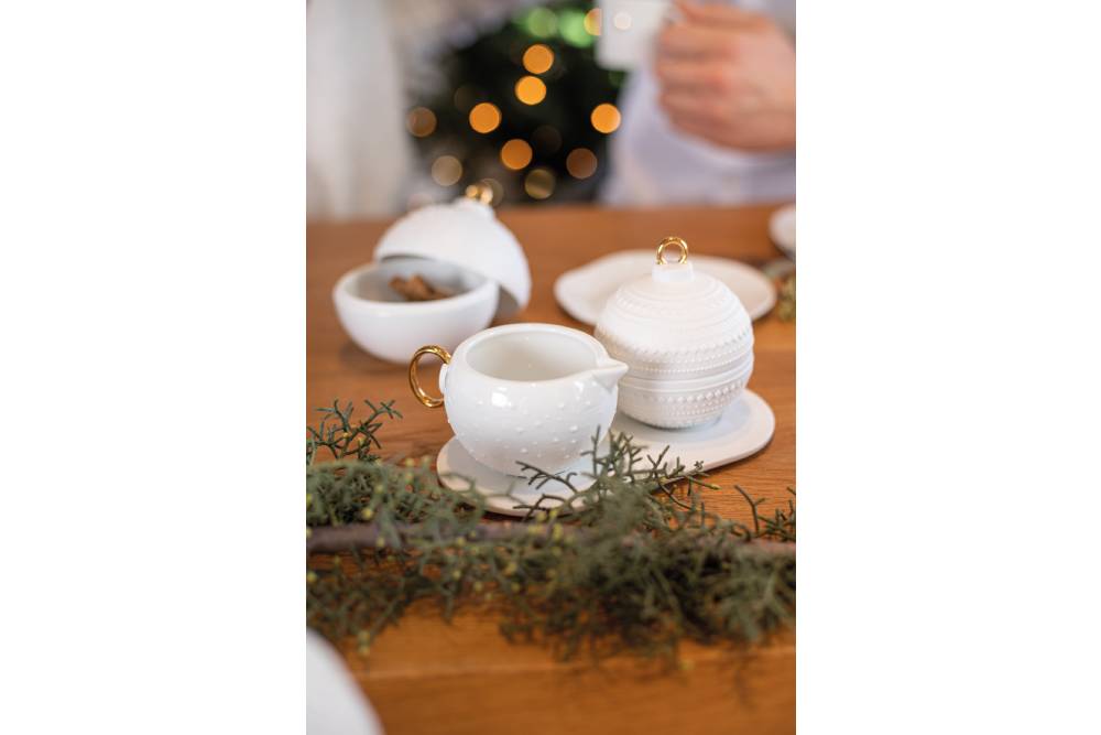 Räder - Wunderkugel "Milch und Zucker" ein Set bestehend aus einer Zuckerdose und eines Milchkännchens in Form einer Weihnachtskugel aus weißem Porzellan mit goldenen Griffen, dazu noch einen Unterteller dekoriert auf dem Esstisch mit Tannenzweigen